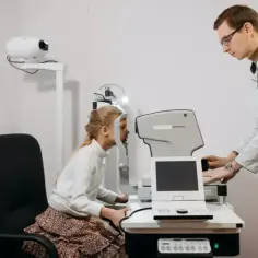 Okulista bada wzrok dziewczynki. Czy do okulisty potrzebne jest skierowanie? Sprawdź, czy wizyta u specjalisty wymaga skierowania.