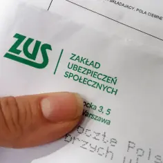 ZUS. Palec wskazuje na dokument z logo ZUS. Może to być cennik lub tabela z odszkodowaniami.