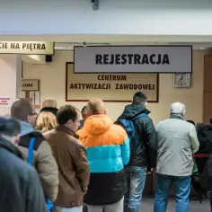 Ludzie stoją w kolejce do rejestracji w centrum aktywizacji zawodowej, czekając na zasilek dla bezrobotnych.