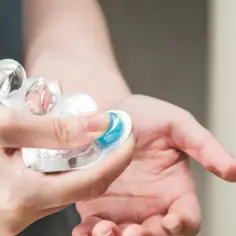 Dłoń wyjmuje niebieską tabletkę z blistra. Czy ibuprofen jest szkodliwy? Zawsze czytaj ulotkę.