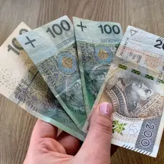 Dłoń trzyma polskie banknoty: 100 zł, 100 zł, 200 zł. Zastanawiasz się, ile dostanę emerytury za 5 lat pracy?
