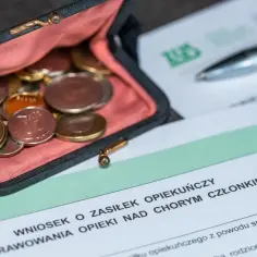 Portmonetka z monetami na tle dokumentów ZUS i długopisu.