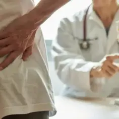 Lekarz pokazuje pacjentowi model kręgosłupa, omawiając leczenie bólu pleców, np. gabapentyną.
