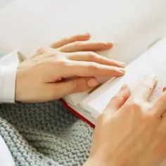 Dłonie czytają książkę Braille'a. To symbol niepełnosprawności, który otwiera drzwi do wiedzy i ulgi.