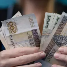Dłonie trzymające plik polskich banknotów 200 zł.