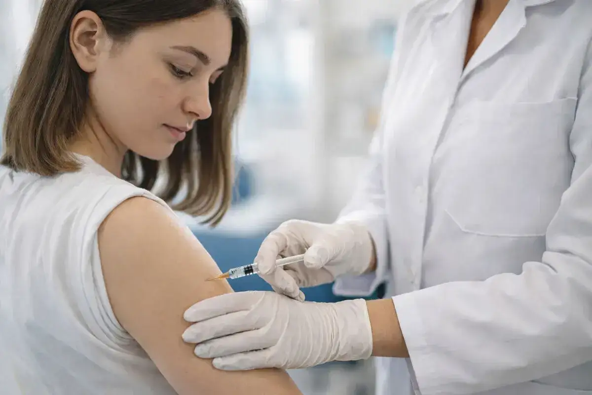 Młoda kobieta otrzymuje zastrzyk. To ważny krok w kierunku szczepienia HPV obowiązkowego, chroniącego przed chorobami.