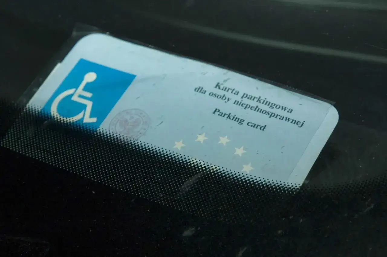 Karta parkingowa z symbolem niepełnosprawności, potwierdzająca uprawnienia do parkowania.