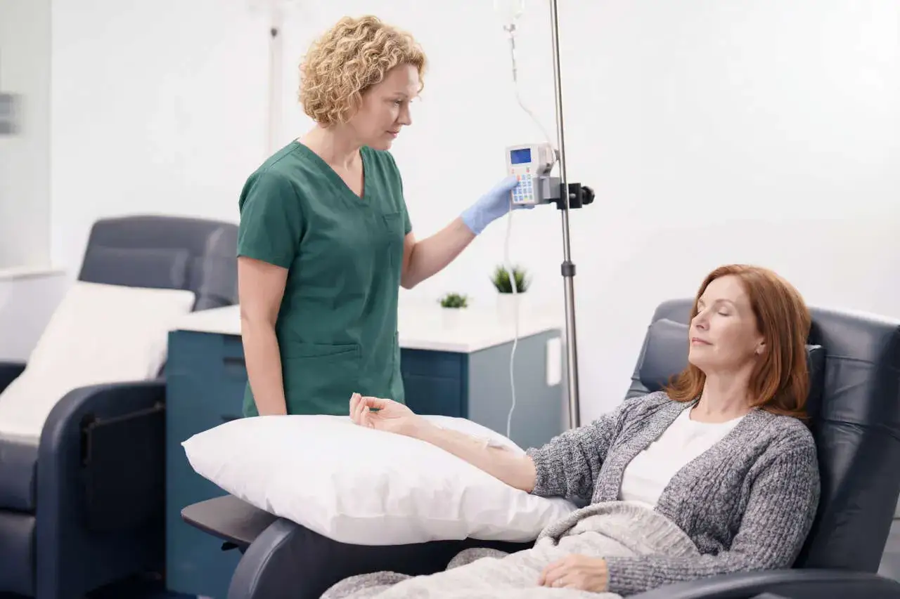 Pielęgniarka nadzoruje kroplówkę z infliksymabem u pacjentki w wygodnym fotelu.