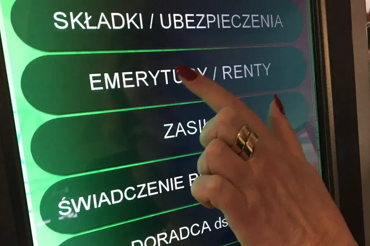 Dłoń z pierścionkiem dotyka ekranu z napisem