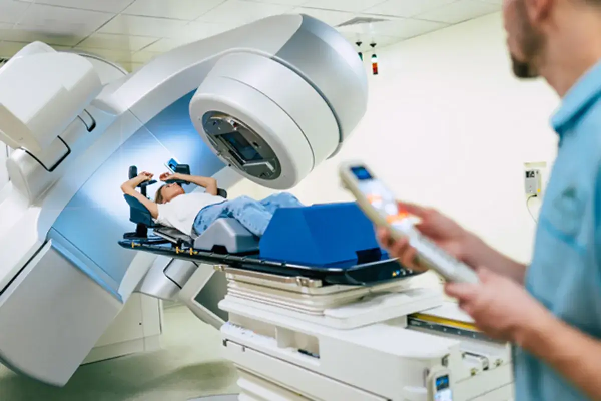 Pacjentka leży na stole terapeutycznym podczas radioterapii, która jest kluczowym elementem w walce z chorobą nowotworową, stanowiąc nadzieję na nowy lek na raka.