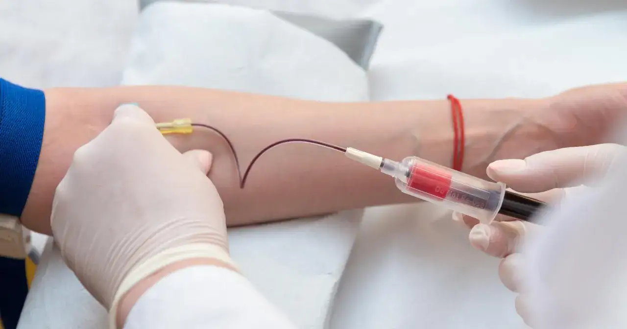 Pobieranie krwi do badania. Lekarz w rękawiczkach pobiera krew z żyły pacjenta, aby sprawdzić m.in. podwyższoną hemoglobinę.